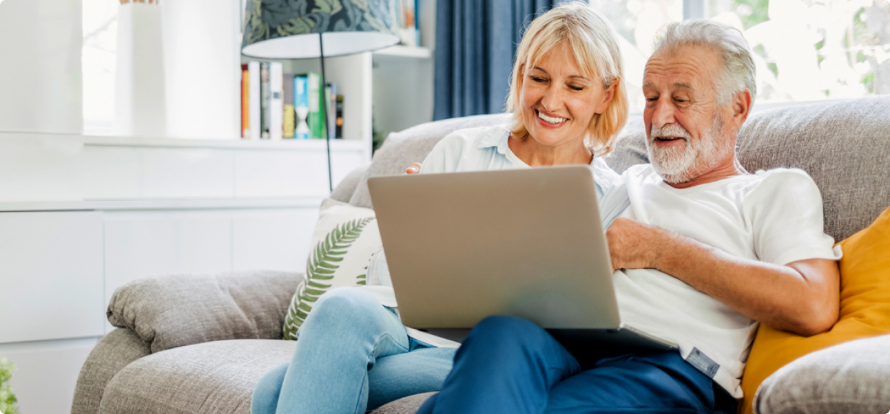 Older couple sitting on a couch looking at a computer