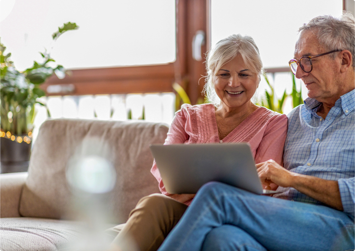 Older couple sitting on a couch looking at a computer