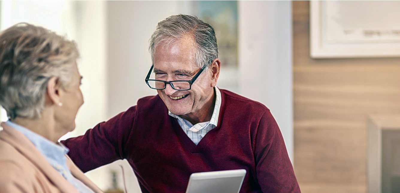 Older couple smiling and looking at bills